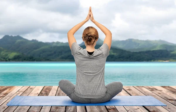Woman doing yoga in lotus pose over ocean — Stock Photo, Image