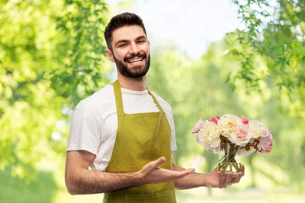 Улыбающийся садовник с кучей пионских цветов — стоковое фото