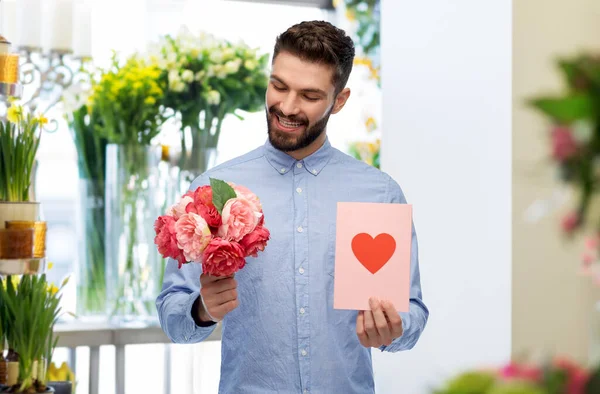 Hombre feliz con flores y tarjeta de San Valentín — Foto de Stock