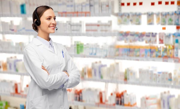 Sorridente médico feminino com fone de ouvido na farmácia — Fotografia de Stock