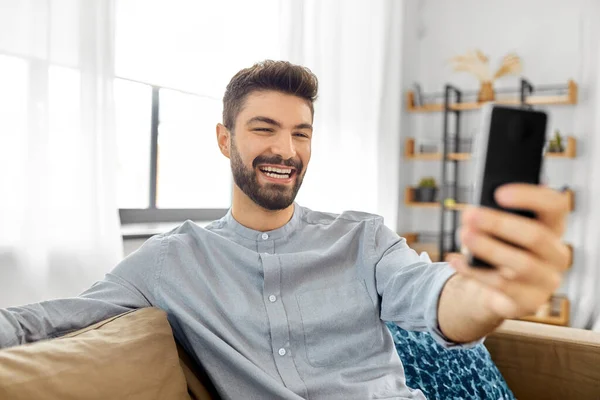 Hombre con teléfono inteligente que tiene videollamada en casa —  Fotos de Stock