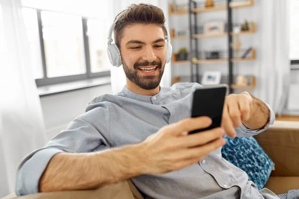 Hombre en auriculares escuchando música en el teléfono inteligente — Foto de Stock