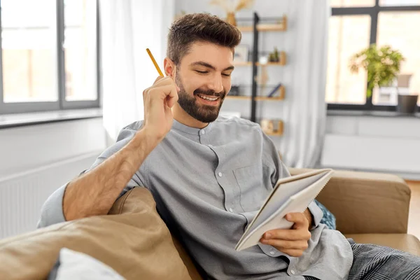 Sorrindo o homem com a caderno e lápis em casa — Fotografia de Stock