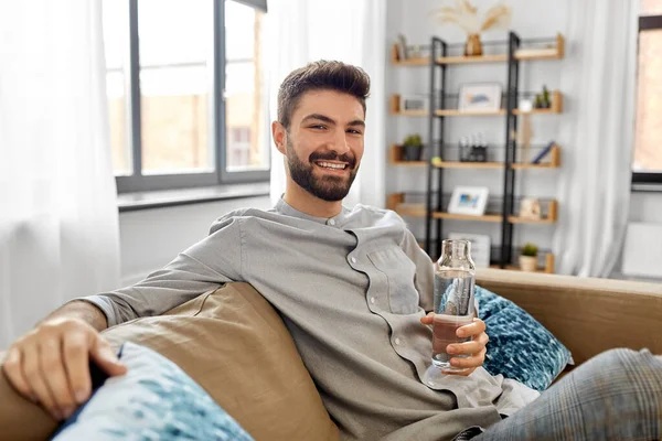 Hombre feliz beber agua de botella de vidrio en casa — Foto de Stock