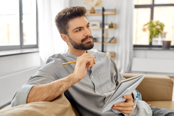Hombre escribiendo a cuaderno y pensando en casa —  Fotos de Stock