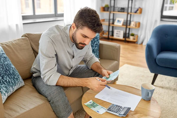 Mann mit Geld und Taschenrechner füllt Papiere aus — Stockfoto