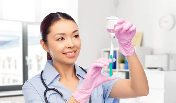 Glad asiatisk kvinnlig sjuksköterska med medicin och spruta — Stockfoto
