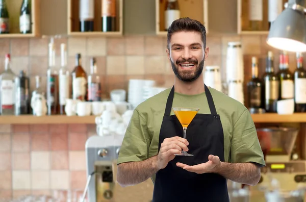 Barman in schort met glas cocktail aan bar — Stockfoto