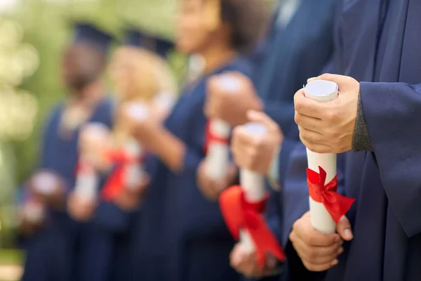 Estudiantes graduados en tableros de mortero con diplomas —  Fotos de Stock