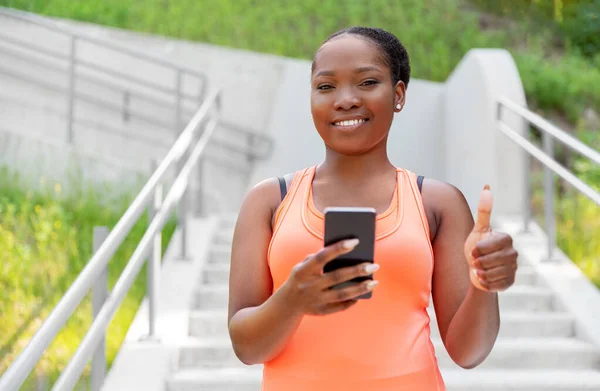 Femme africaine sportive souriante utilisant un smartphone — Photo