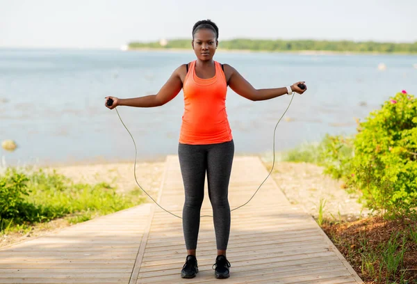 Mujer africana haciendo ejercicio con cuerda de salto en la playa — Foto de Stock
