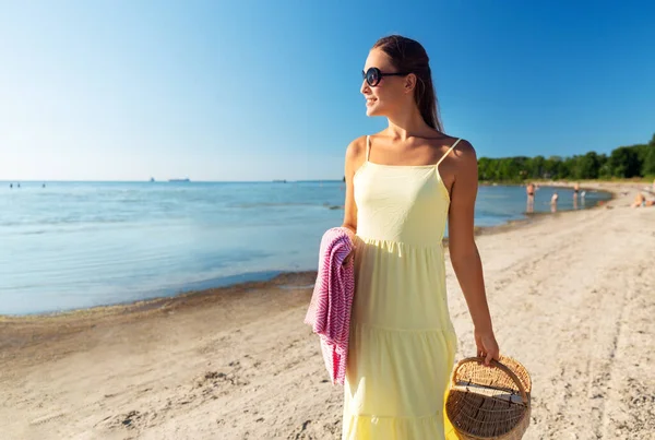 Szczęśliwa kobieta z koszykiem piknikowym spacerująca wzdłuż plaży — Zdjęcie stockowe