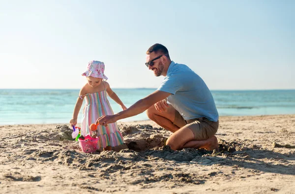 Far och dotter leker med leksaker på stranden — Stockfoto