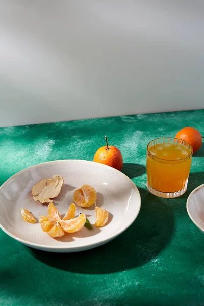 Mandarini pelati su piatto e vetro di succo di frutta — Foto Stock