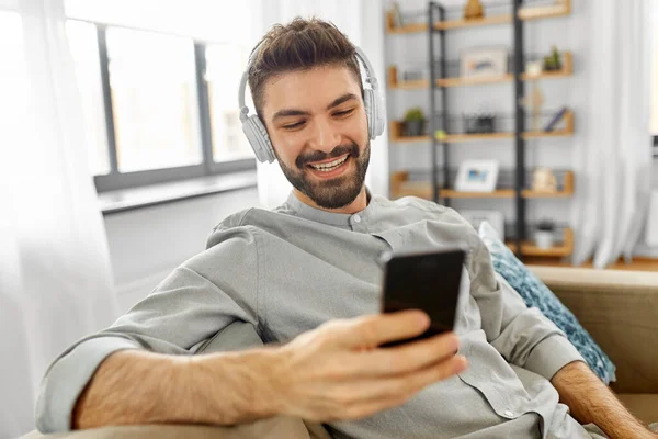 Hombre en auriculares escuchando música en el teléfono inteligente — Foto de Stock