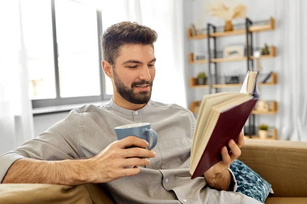 Hombre leyendo libro y bebiendo café en casa — Foto de Stock