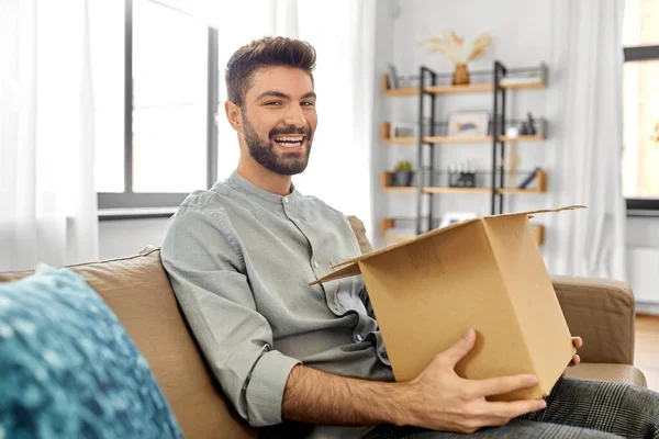 Feliz hombre sonriente abriendo la caja de paquetes en casa — Foto de Stock