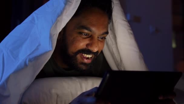 Hombre indio con tableta pc en la cama en casa por la noche — Vídeos de Stock