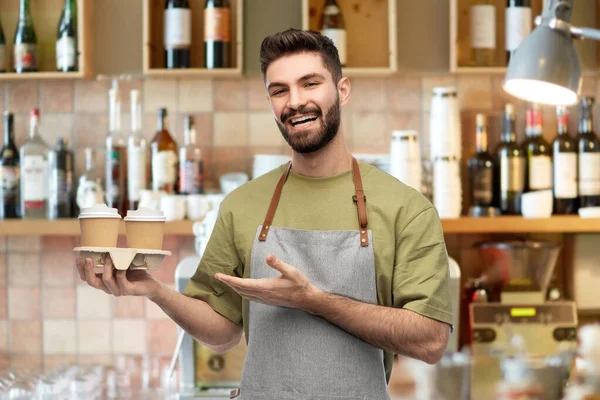 Feliz sorridente barman em avental com takeaway café — Fotografia de Stock