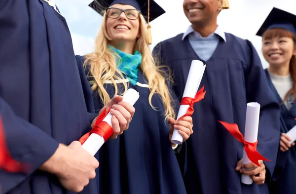 Estudiantes graduados en tableros de mortero con diplomas —  Fotos de Stock