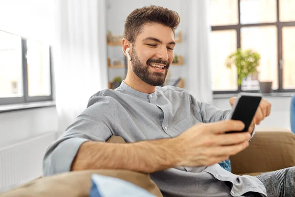 Hombre en auriculares escuchando música en el teléfono inteligente — Foto de Stock