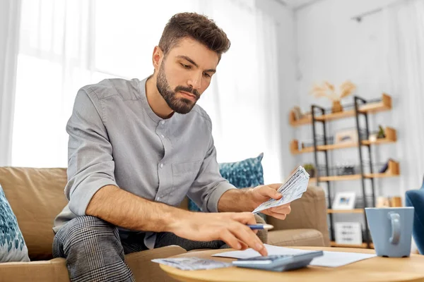 Man med pengar och kalkylator fylla papper — Stockfoto