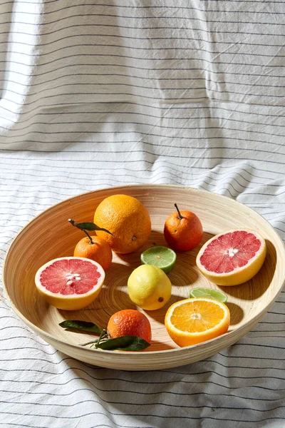 Close up of citrus fruits on wooden plate — Stock Photo, Image