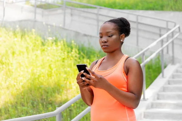 Sportieve Afrikaanse vrouw met behulp van smartphone in de stad — Stockfoto