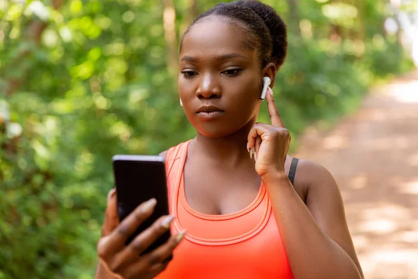 Mulher americana africana com fones de ouvido e telefone — Fotografia de Stock