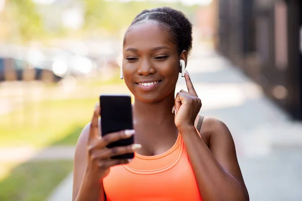 Mulher americana africana com fones de ouvido e telefone — Fotografia de Stock