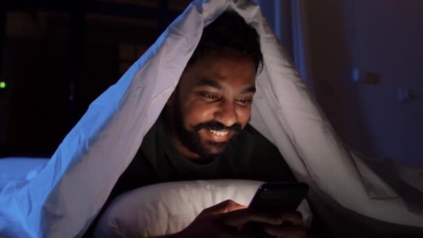 Indiaanse man met smartphone in bed thuis 's nachts — Stockvideo