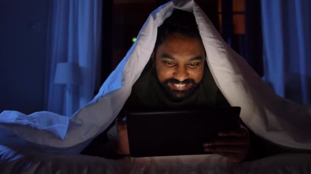 Чоловік з планшетом у ліжку вночі. — стокове відео