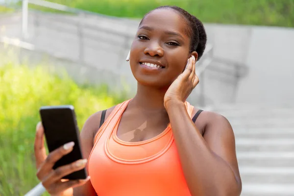 Mulher americana africana com fones de ouvido e telefone — Fotografia de Stock