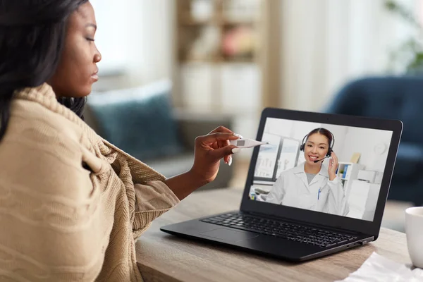 Mujer enferma que tiene videollamada con médico en el ordenador portátil —  Fotos de Stock