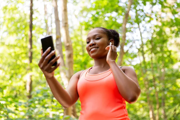 Афроамериканська жінка з навушниками та телефоном — стокове фото