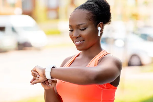 Mulher africana feliz com fones de ouvido e relógio inteligente — Fotografia de Stock