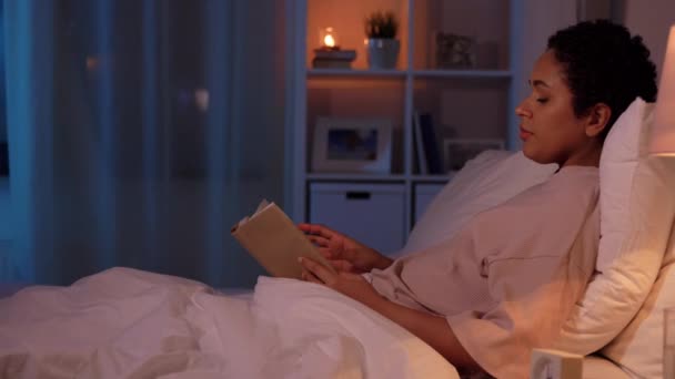 Mladá žena čtení knihy v posteli doma — Stock video