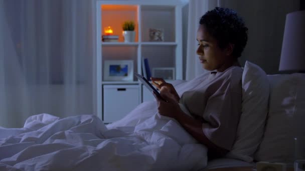 Жінка з планшетним ПК в ліжку вдома вночі — стокове відео