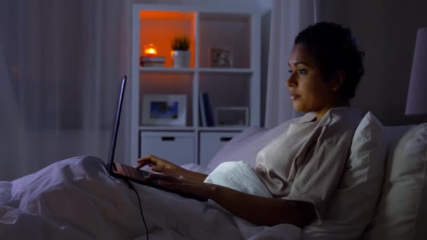 Жінка з ноутбуком в ліжку вдома вночі — стокове відео