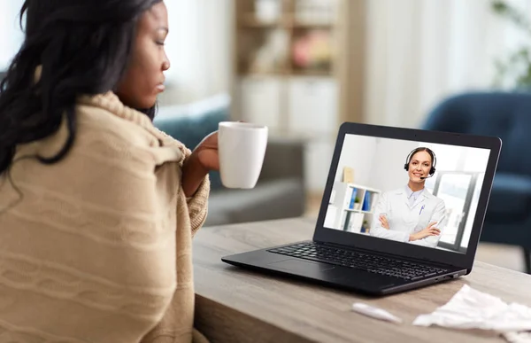 Хвора жінка має відеодзвінок з лікарем на ноутбуці — стокове фото