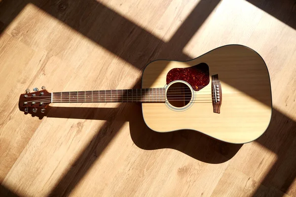 Zblízka akustické kytary na dřevěné podlaze — Stock fotografie