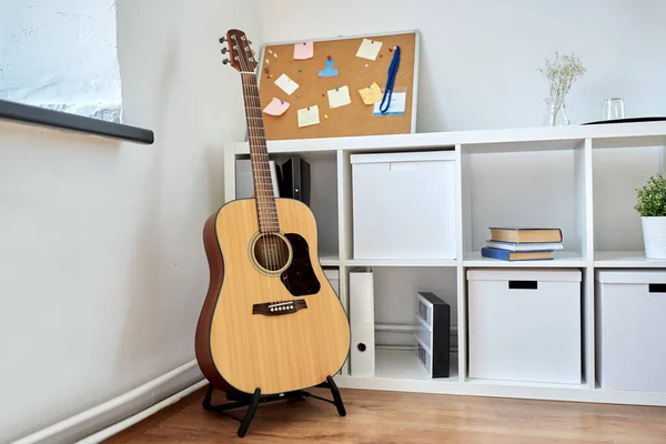 Zblízka akustické kytary na stojanu doma — Stock fotografie