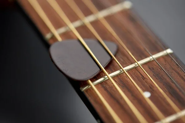 Primer plano de cuello de guitarra con pico entre cuerdas — Foto de Stock