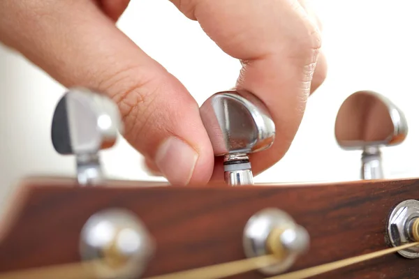 Close up of hand tuning guitar strings with pegs — Stock Photo, Image