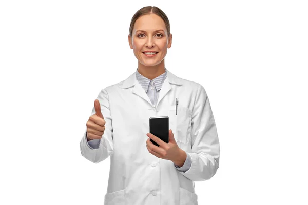 Kobieta lekarz ze smartfonem pokazuje kciuki do góry — Zdjęcie stockowe