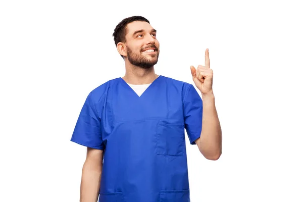Médico sonriente o enfermero masculino apuntando con el dedo hacia arriba — Foto de Stock