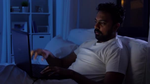 Indisk mand lukker bærbar computer i sengen hjemme om natten – Stock-video
