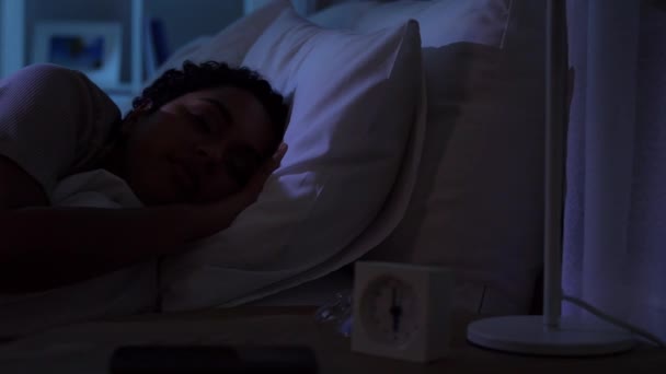 Спящая женщина просыпается из-за телефона ночью — стоковое видео