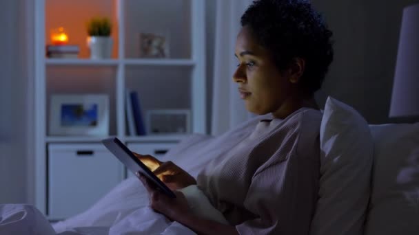 Жінка з планшетним ПК в ліжку вдома вночі — стокове відео