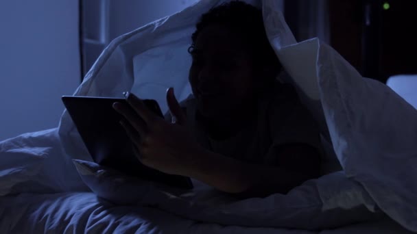 Mulher com tablet pc sob cobertor na cama à noite — Vídeo de Stock